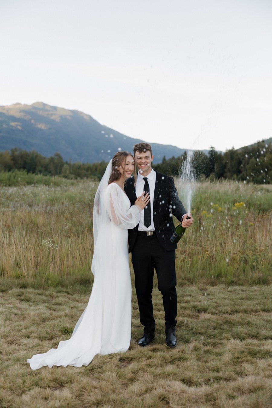 Couple celebrating with champagne in the meadow at Eden Farm